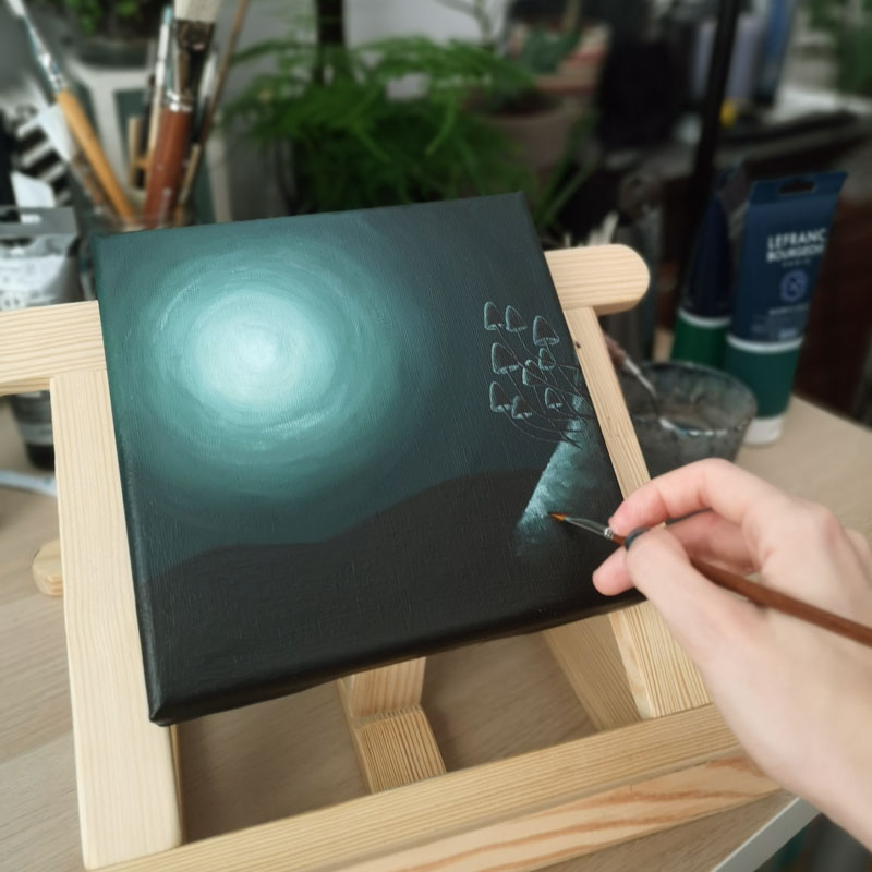 hand painting a green painting on an easel